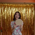 Photobooth DIY fait maison avec rideau de franges dorées et accessoires amusants lors d'une fête d'anniversaire