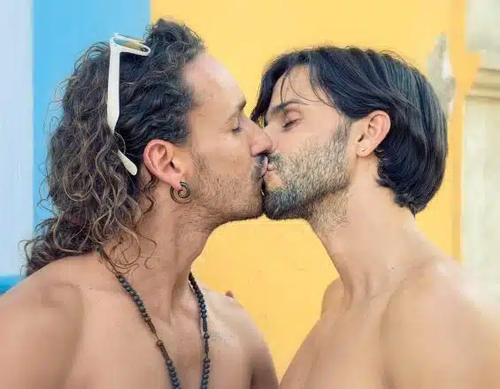 two men with long hair are kissing each other
